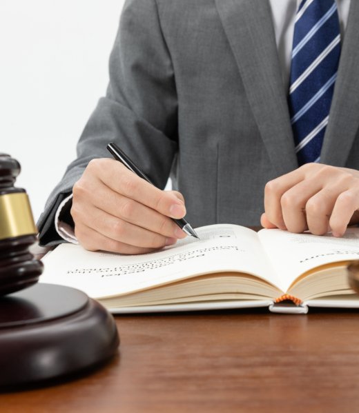 closeup-shot-person-writing-book-with-gavel-table